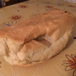 A loaf of white bread with hand pushed through